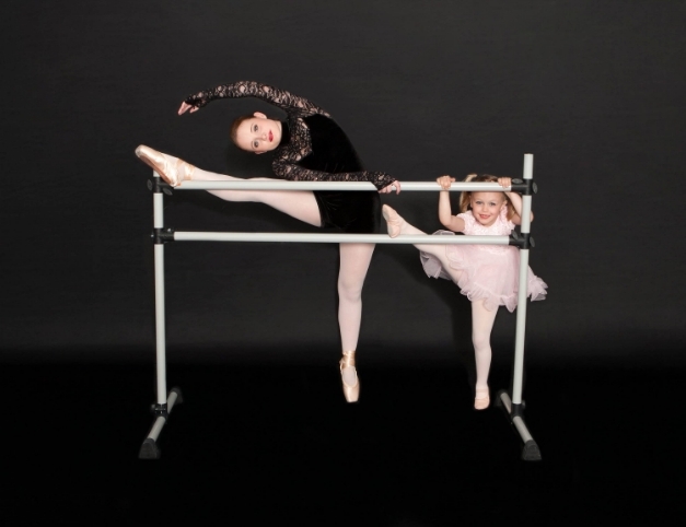 two girls doing stretches on dance bar