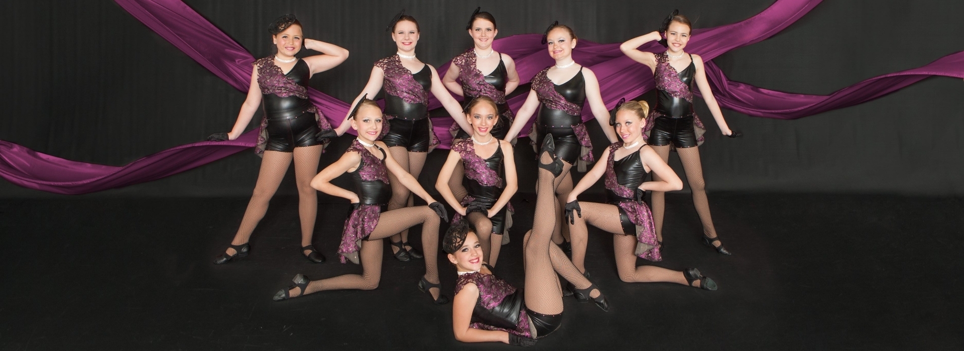 dancers posing on stage in front of pink ribbons